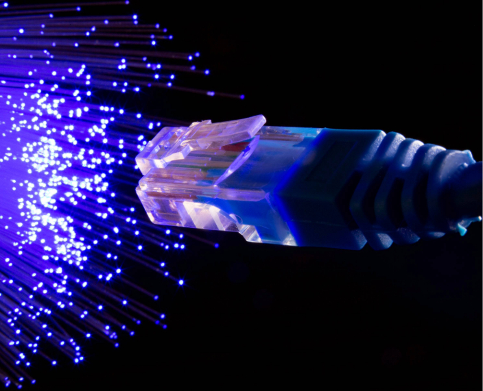 Nahaufnahme von Glasfasersträngen mit leuchtenden Lichtimpulsen zur Datenübertragung.