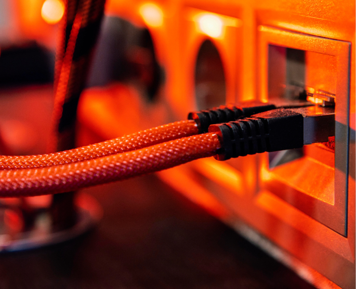 Mehrere Netzwerkkabel vor einem Hintergrund mit roter Beleuchtung in einem abstrakten Technologie-Setting.