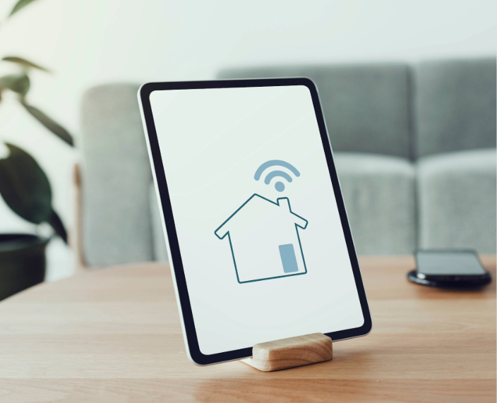 Ein Tablet auf einem Holztisch zeigt eine Smart-Home Benutzeroberfläche zur Steuerung von Geräten und Einstellungen.